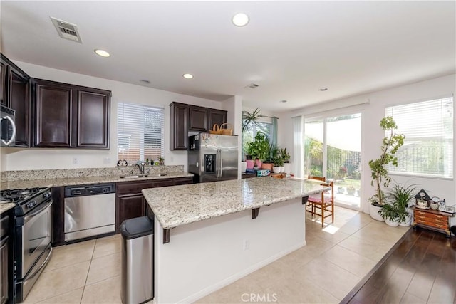 kitchen with dark brown cabinetry, visible vents, a breakfast bar, a center island, and stainless steel appliances
