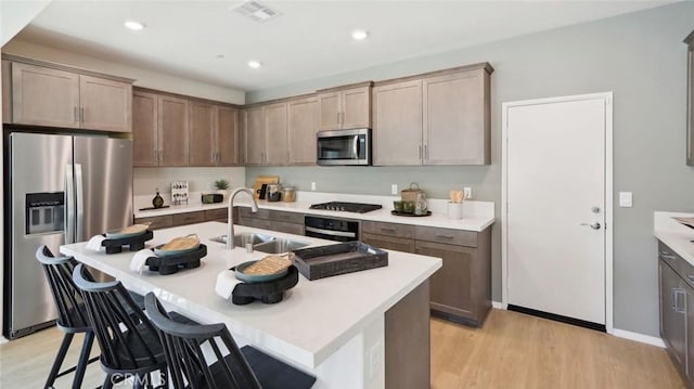 kitchen featuring a kitchen bar, stainless steel appliances, a sink, and light countertops