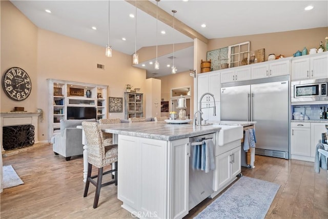 kitchen featuring built in appliances, visible vents, light wood-type flooring, and white cabinetry