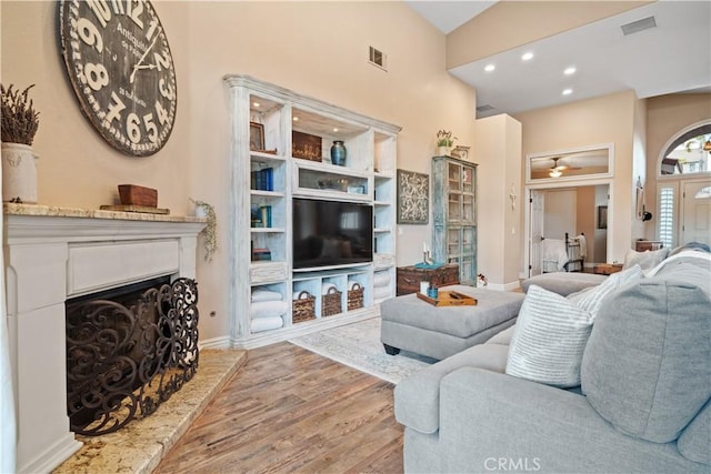 living room with visible vents, a fireplace with raised hearth, wood finished floors, and recessed lighting