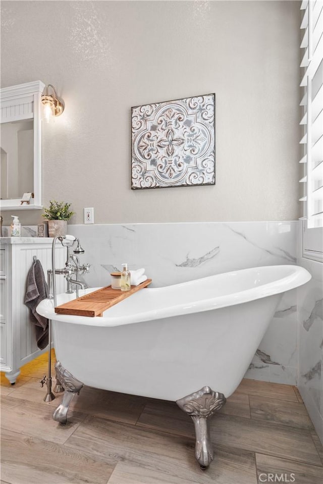 bathroom featuring a wainscoted wall and a freestanding bath