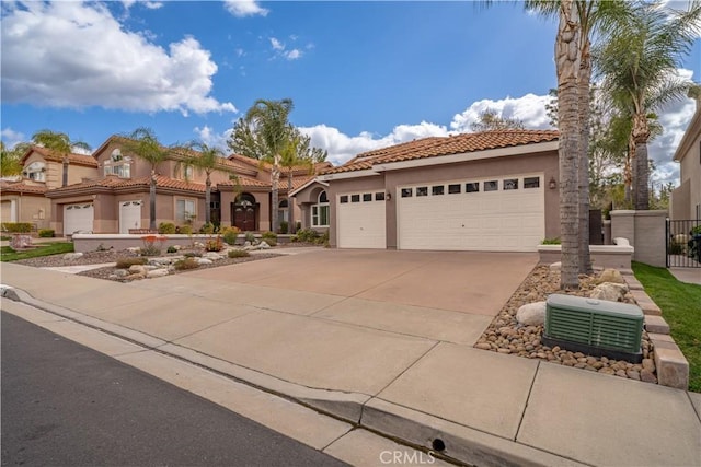 mediterranean / spanish home with a tile roof, central air condition unit, stucco siding, concrete driveway, and an attached garage