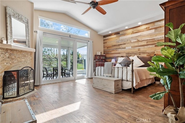 unfurnished bedroom featuring access to outside, multiple windows, wooden walls, and wood finished floors