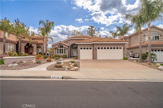 mediterranean / spanish home featuring a garage, driveway, a tiled roof, and stucco siding