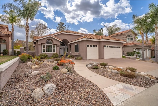 mediterranean / spanish-style home with a garage, a tile roof, driveway, and stucco siding