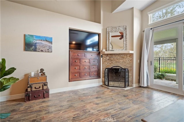 unfurnished living room featuring baseboards, a fireplace with raised hearth, and wood finished floors