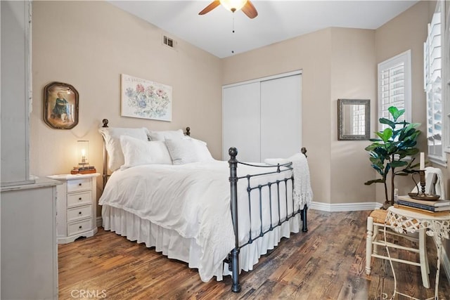 bedroom featuring baseboards, a closet, visible vents, and wood finished floors