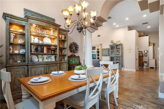 dining area with a chandelier, arched walkways, visible vents, and wood finished floors