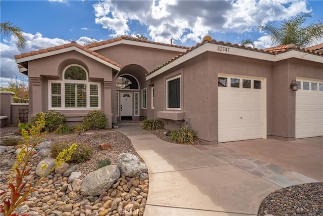 mediterranean / spanish-style home with concrete driveway, a tile roof, an attached garage, and stucco siding