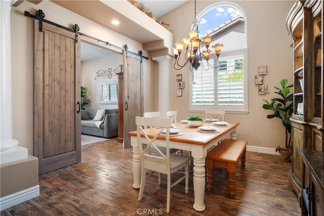 dining area featuring a barn door, decorative columns, baseboards, dark wood-style flooring, and a chandelier