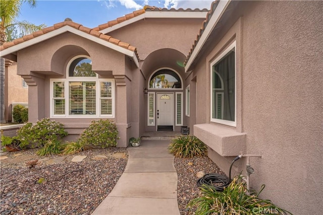 doorway to property with a tiled roof and stucco siding