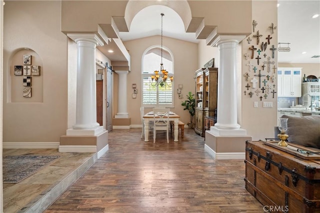 interior space featuring a chandelier, vaulted ceiling, decorative columns, and wood finished floors