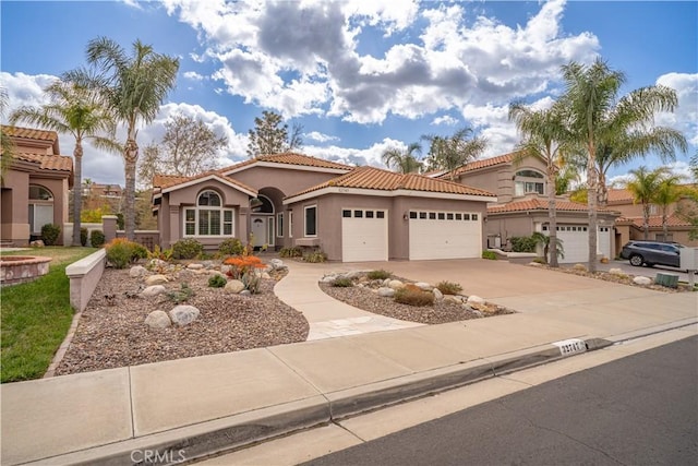 mediterranean / spanish-style home with driveway, a tile roof, a garage, and stucco siding