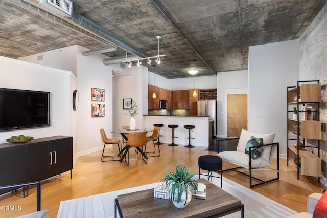 living area featuring light wood-style floors, baseboards, and visible vents