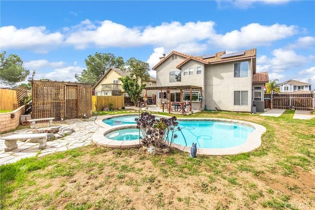 back of house featuring a fenced in pool, an in ground hot tub, a fenced backyard, and solar panels