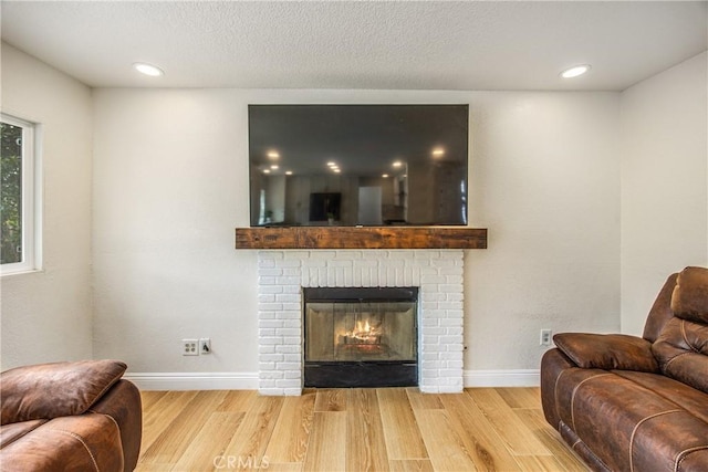 living room with baseboards, wood finished floors, a textured ceiling, a fireplace, and recessed lighting