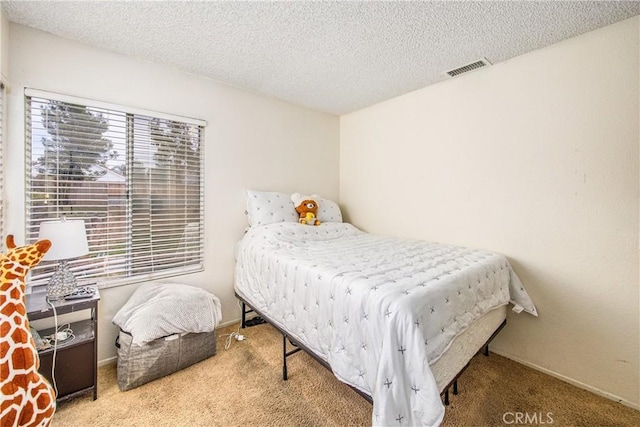 bedroom with carpet, visible vents, and a textured ceiling