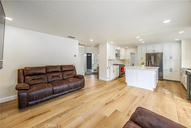 living room featuring recessed lighting, visible vents, a textured ceiling, light wood-type flooring, and baseboards