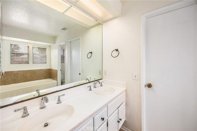 full bath with visible vents, a sink, toilet, and double vanity