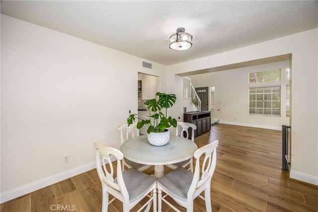 dining space featuring wood finished floors, visible vents, and baseboards