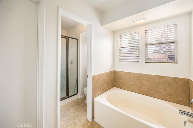 bathroom with a stall shower, tile patterned floors, toilet, and a bath