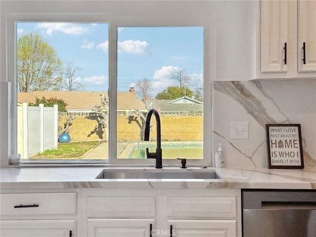 room details featuring decorative backsplash, white cabinetry, a sink, and stainless steel dishwasher