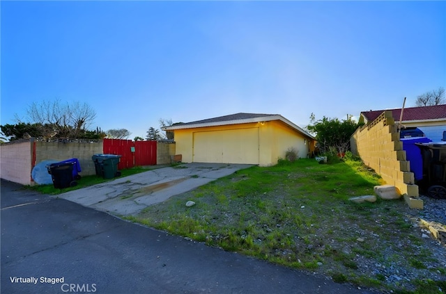 view of side of home featuring a garage, an outdoor structure, and fence