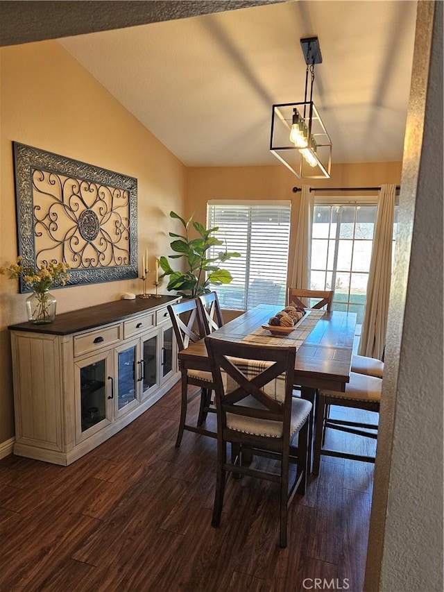 dining area featuring dark wood-style flooring, a healthy amount of sunlight, and vaulted ceiling