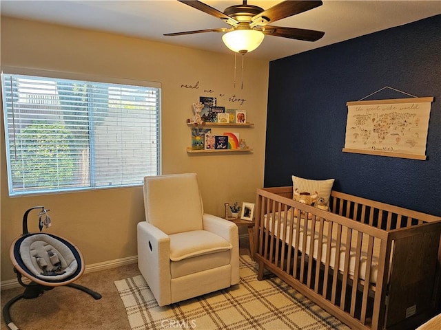 bedroom with carpet, ceiling fan, a crib, and baseboards