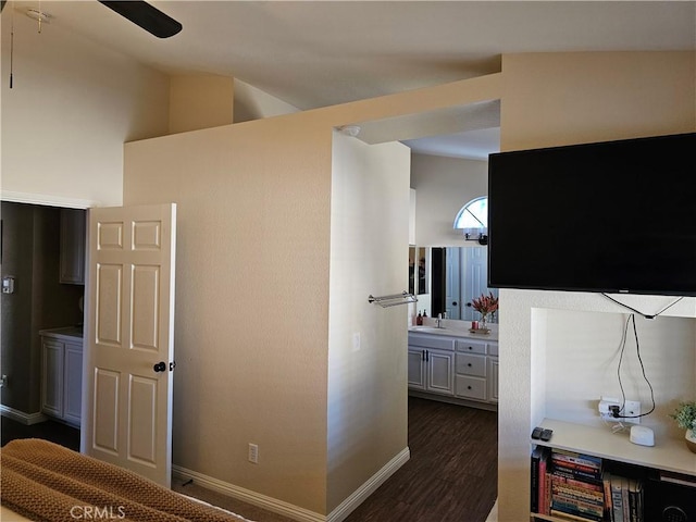 interior space with dark wood finished floors, a sink, lofted ceiling, and baseboards