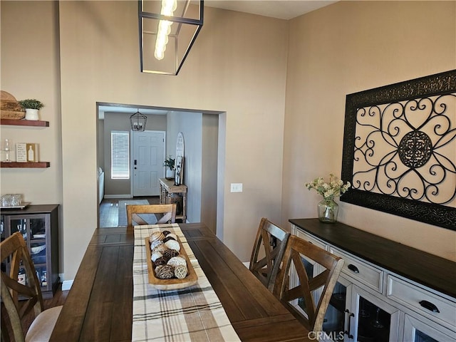 dining room featuring beverage cooler, a towering ceiling, and baseboards