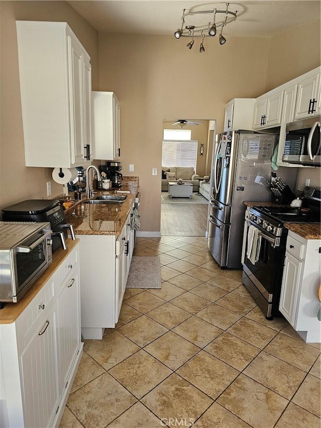 kitchen featuring stainless steel appliances, white cabinetry, a sink, and light tile patterned flooring