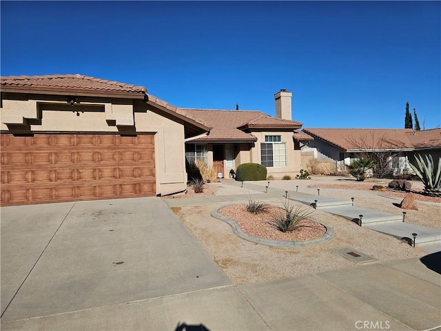 view of front of property with a garage, concrete driveway, a chimney, a tiled roof, and stucco siding