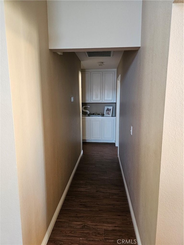 corridor featuring baseboards, visible vents, and dark wood-style flooring