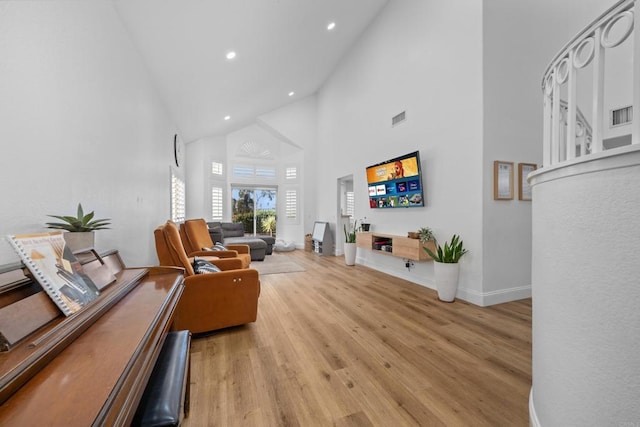 living room featuring high vaulted ceiling, visible vents, baseboards, and wood finished floors