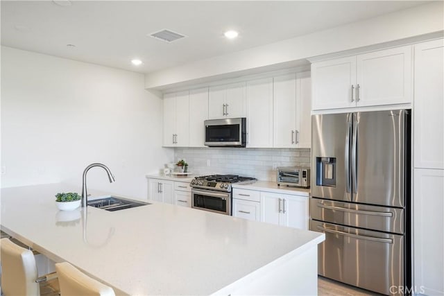 kitchen featuring white cabinets, appliances with stainless steel finishes, a sink, and visible vents
