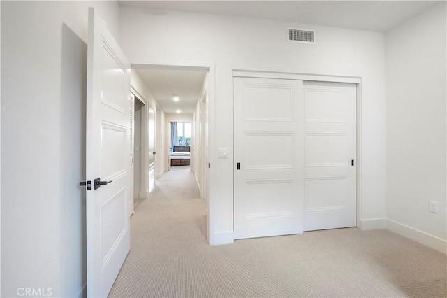 unfurnished bedroom with baseboards, light carpet, a closet, and visible vents