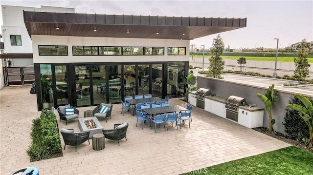 view of patio / terrace with outdoor dining area, a fire pit, grilling area, and an outdoor kitchen