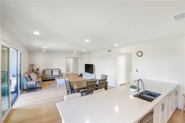 interior space with visible vents, light countertops, white cabinetry, a sink, and light wood finished floors