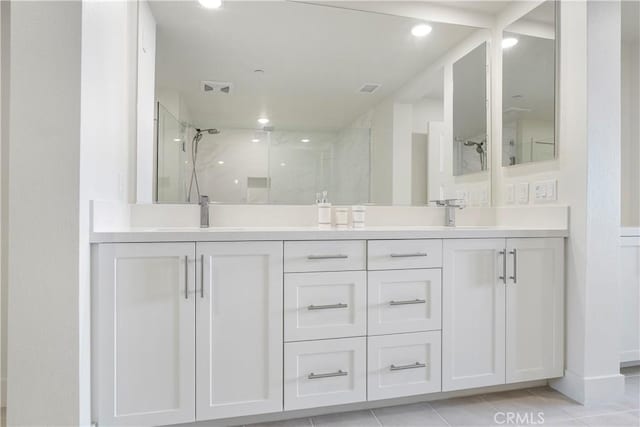 bathroom with double vanity, a sink, a marble finish shower, and visible vents