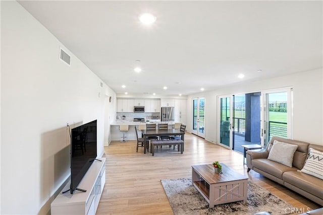 living area with recessed lighting, visible vents, and light wood finished floors