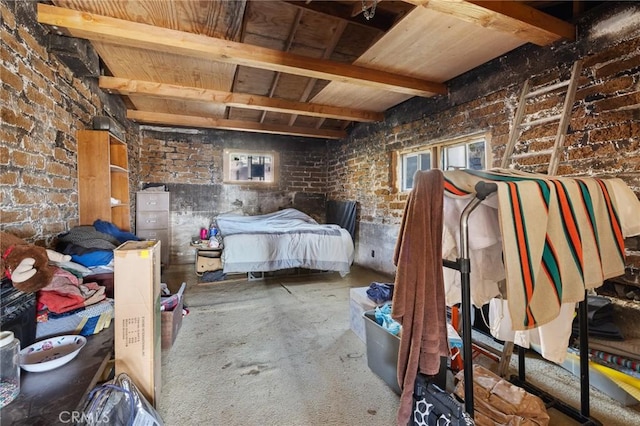 bedroom with beam ceiling, concrete floors, and brick wall