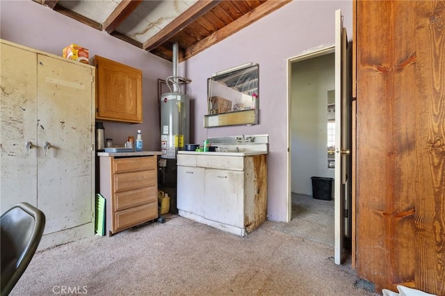 kitchen with beam ceiling, light countertops, water heater, light carpet, and wooden ceiling