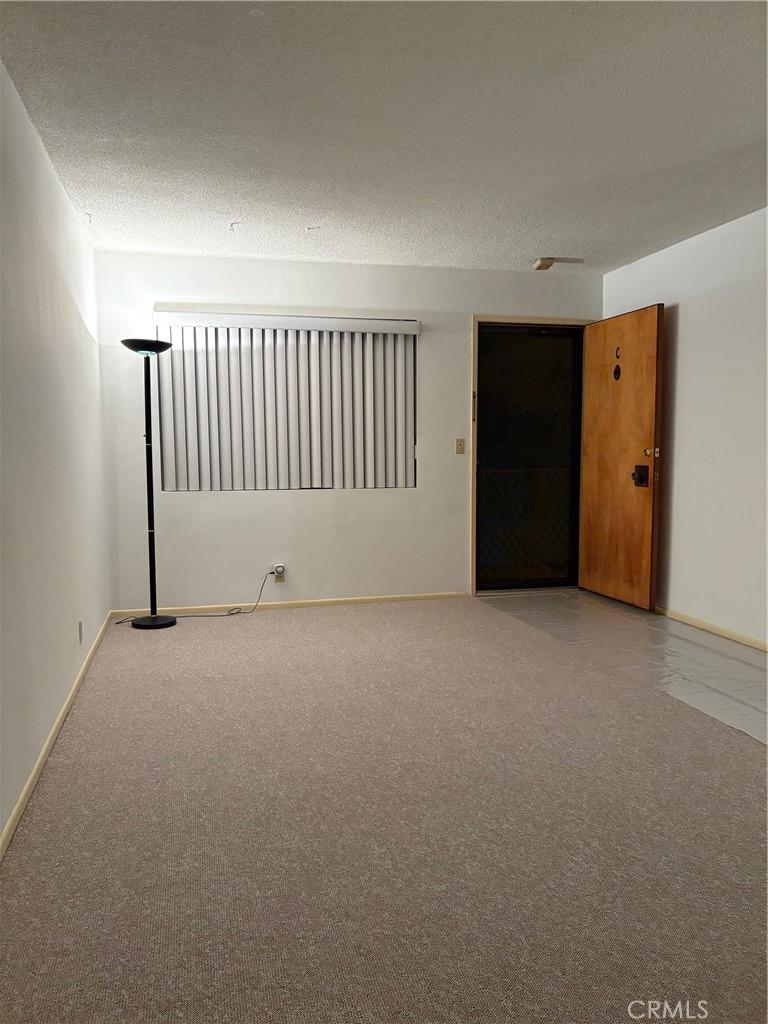 unfurnished room with carpet floors, a textured ceiling, and baseboards