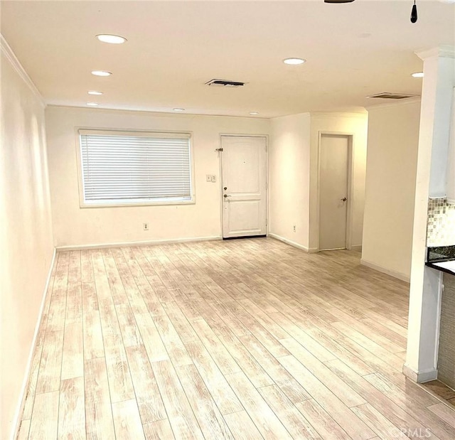 spare room featuring light wood-style floors, baseboards, and visible vents