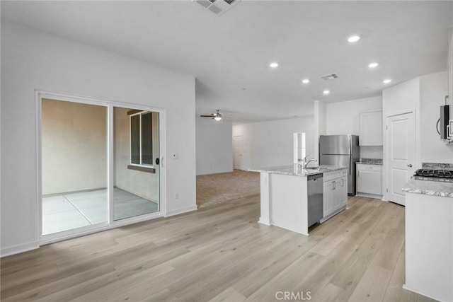 kitchen with open floor plan, stainless steel appliances, light wood-style flooring, and visible vents