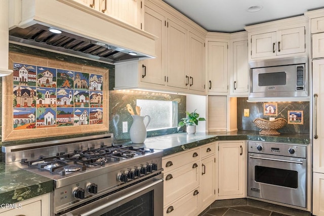 kitchen with dark stone counters, stainless steel appliances, custom exhaust hood, and decorative backsplash