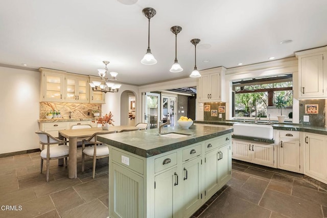 kitchen with dark countertops, arched walkways, backsplash, and stone tile flooring