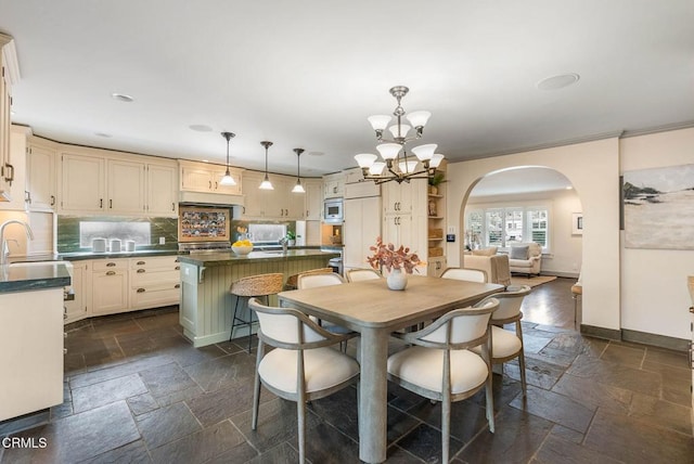 dining room with arched walkways, baseboards, a chandelier, and stone tile floors