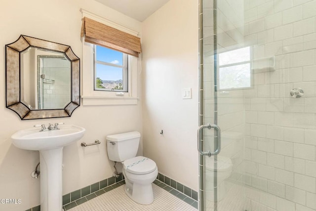 full bath with a stall shower, baseboards, toilet, tile patterned floors, and a sink